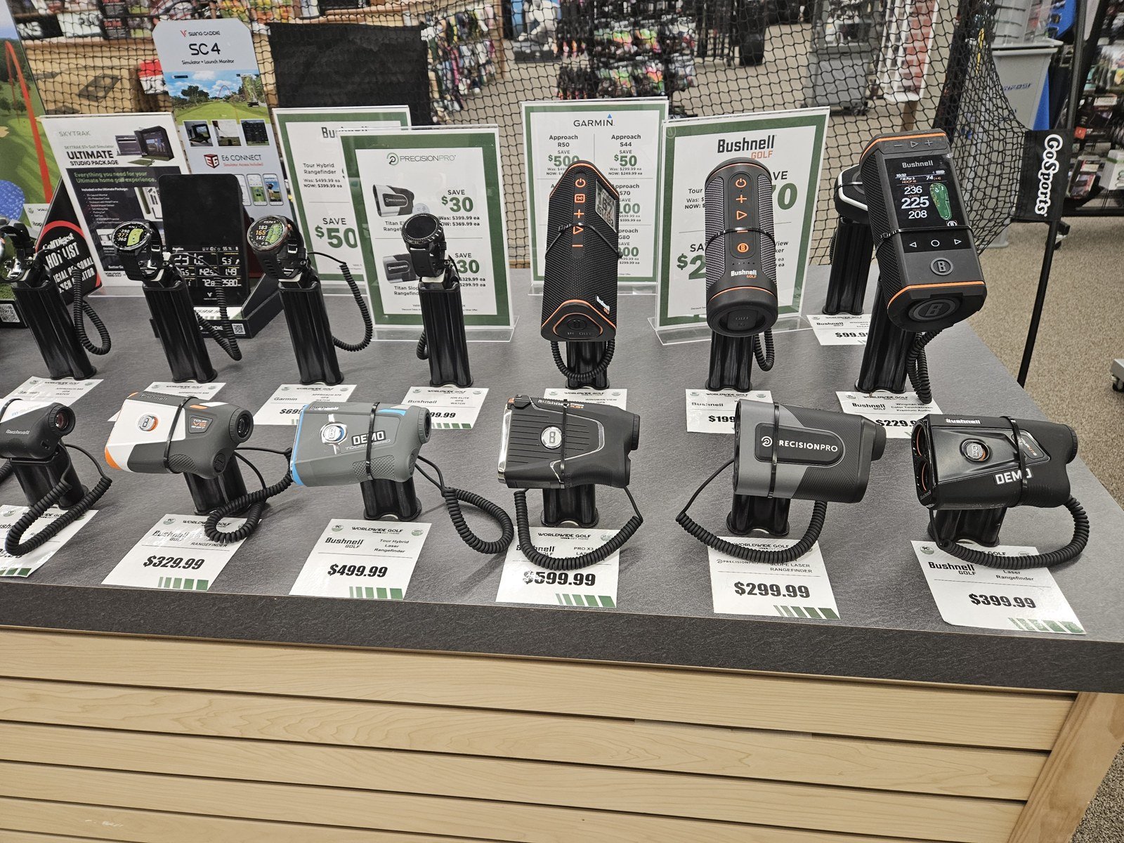 Retail display of golf rangefinders and shelf tags, including Bushnell models.