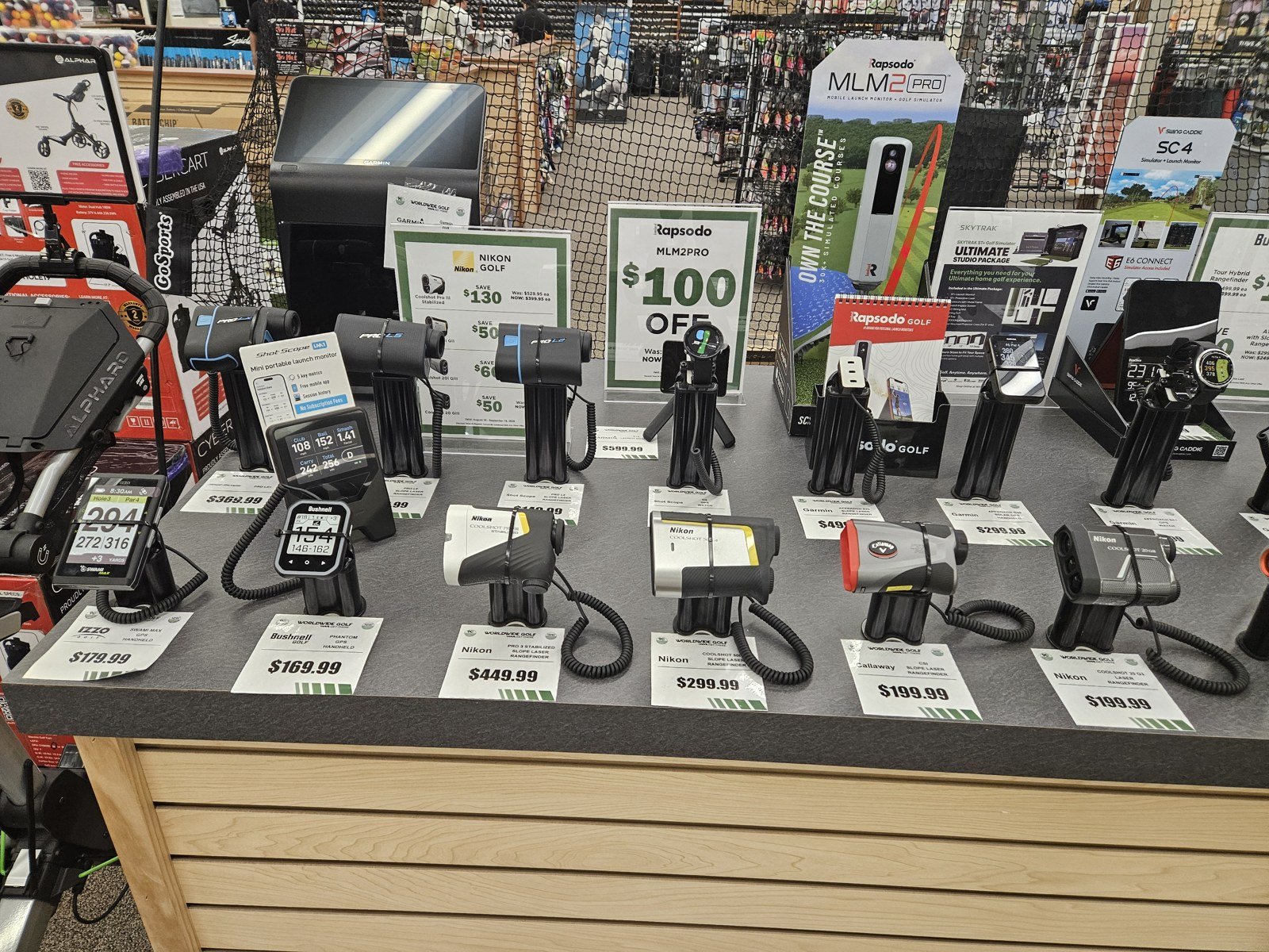 Retail display of golf rangefinders and shelf tags, including Bushnell models.